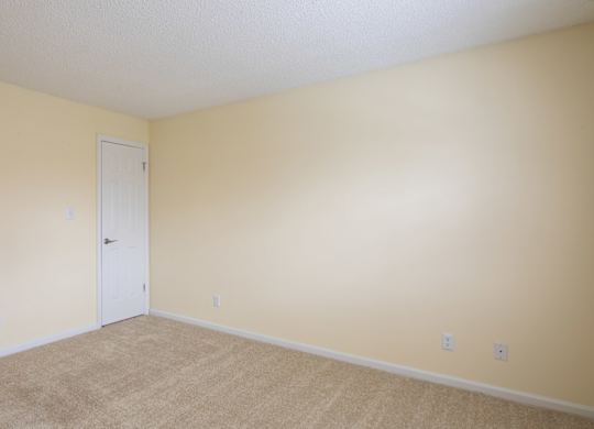 A room with a white door and beige walls.