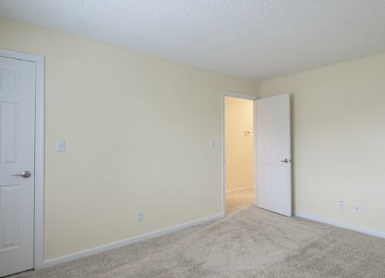 A room with two doors and carpeted floor.
