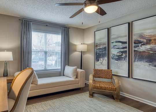 A living room with a couch, a chair, a table, and a ceiling fan.