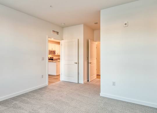 A spacious room with white walls and a carpeted floor.