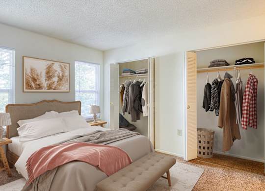 A bedroom with a bed, a clothing rack, and a painting on the wall at The Everett  Apartments in Roanoke, 24018
