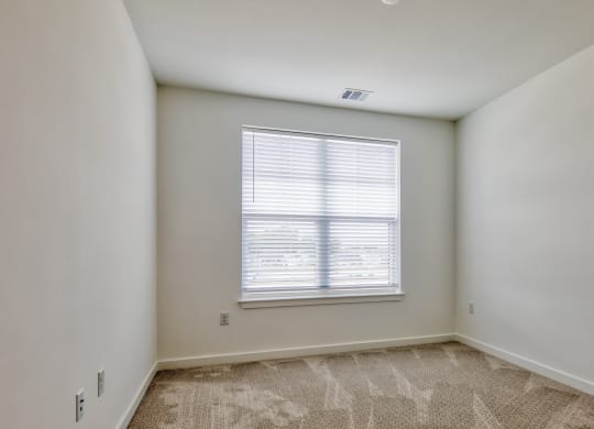 an empty bedroom with a large window and carpeted flooring at Allure at Edinburgh, Virginia