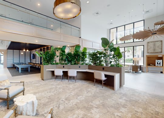 a large lobby with a table with chairs and plants