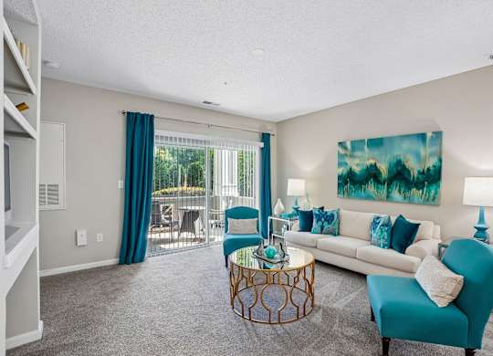 A living room with a blue chair and a painting on the wall.