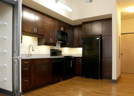 A kitchen with black appliances and wooden cabinets.