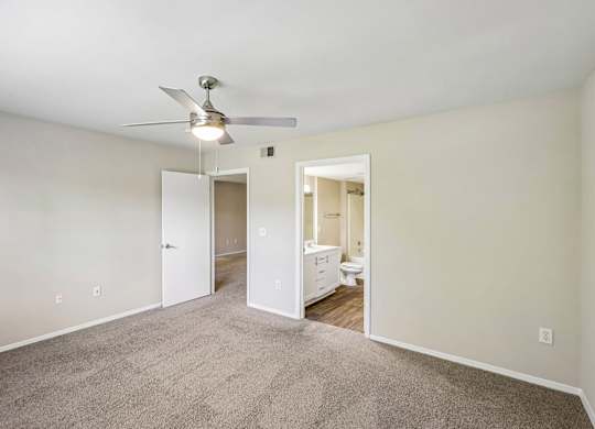 A room with a ceiling fan and carpeted floor.