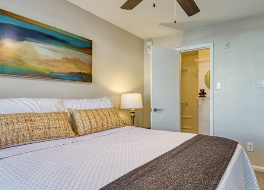 A bedroom with a large bed and a painting on the wall.