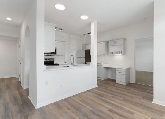 an open kitchen and living room with white walls and wood flooring at The Charleston, Ohio