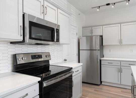 a kitchen with white cabinets and stainless steel appliances at The Charleston, Columbus, OH