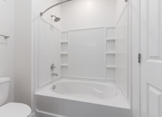 a white bathroom with a tub and a toilet at The Charleston, Columbus
