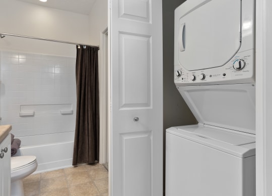 a white washer and dryer in a bathroom with a shower and a toilet at The Charleston, Columbus, Ohio