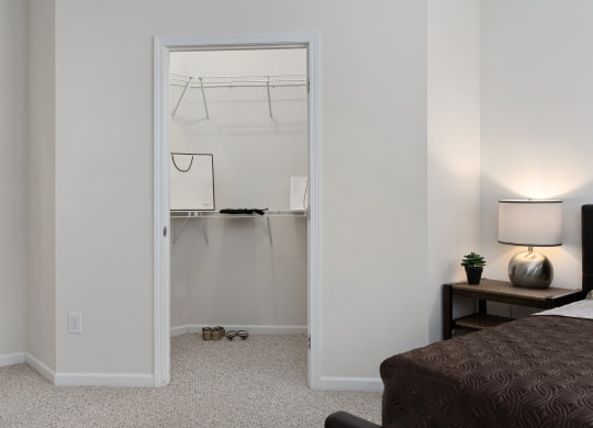 a bedroom with a closet and a bed and a night stand with a lamp at The Charleston, Columbus