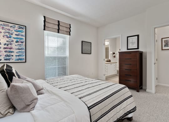 a bedroom with a bed and a dresser and a bathroom at The Charleston, Columbus
