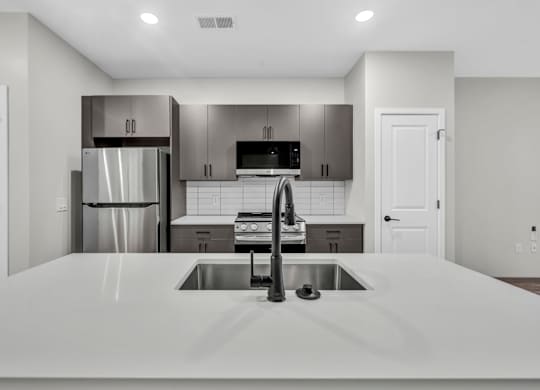 A modern kitchen with a stainless steel refrigerator and a white countertop.