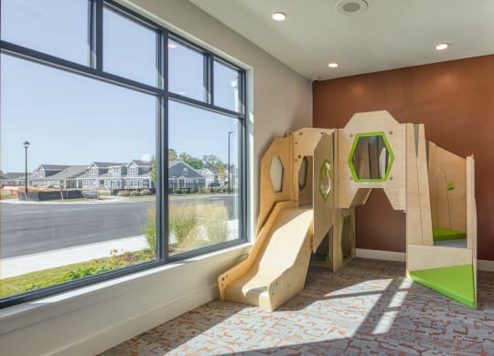 a childs play room with a large window and a wooden play structure