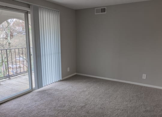 an empty living room with a sliding glass door to a balcony