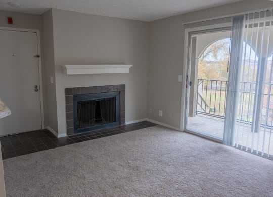 an empty living room with a fireplace and a patio door