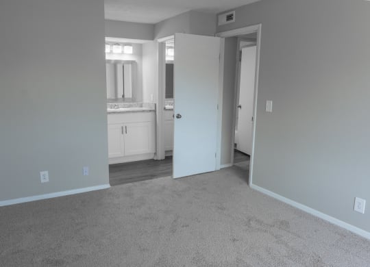an empty living room with a white carpet and a bathroom