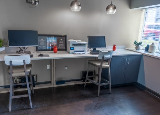 a computer desk with three stools and two monitors