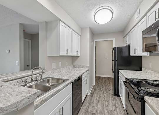 A kitchen with white cabinets and a black refrigerator.
