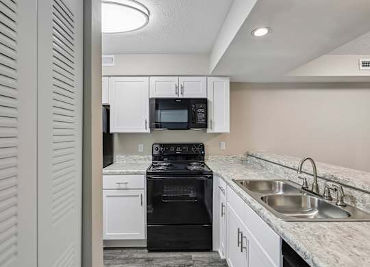 A kitchen with a black stove top oven and a microwave above the stove.