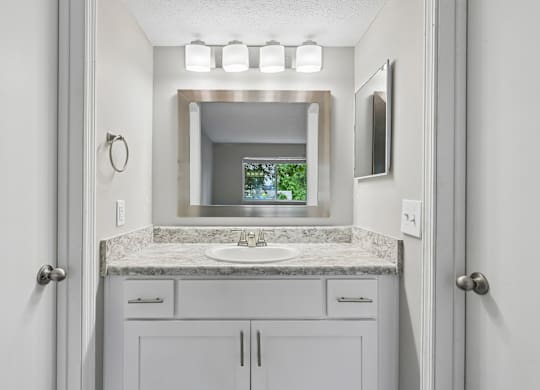 A bathroom with a sink, mirror, and cabinets.