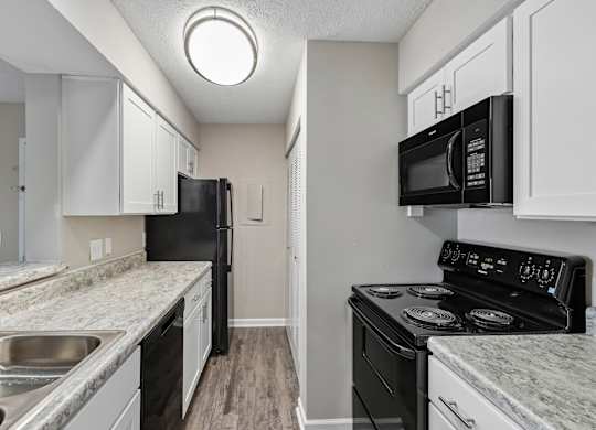 A kitchen with black appliances and white cabinets.