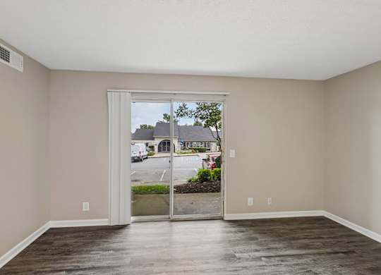A room with a sliding glass door leading to a parking lot.