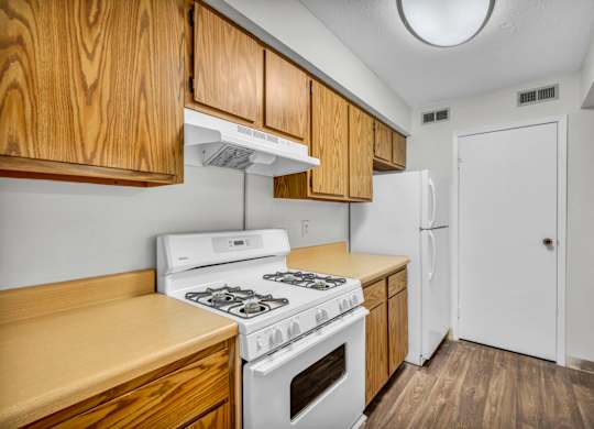 A kitchen with a white stove and wooden cabinets.