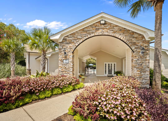 the archway of a house with a walkway and palm trees