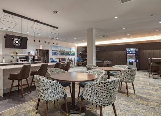 A modern dining area with a kitchen in the background at Residences at Richmond Trust in Richmond, VA, 23219