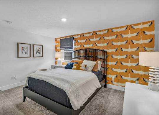 A bedroom with a bed, pillows, and pictures on the wall.