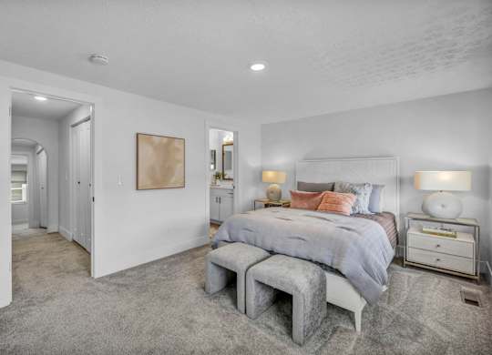 A bedroom with a bed, nightstand, and a grey tufted bench.