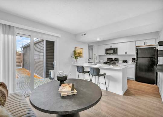 A modern kitchen with a black fridge and white cabinets.