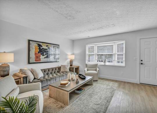 A living room with a grey couch, a coffee table, and a painting on the wall.