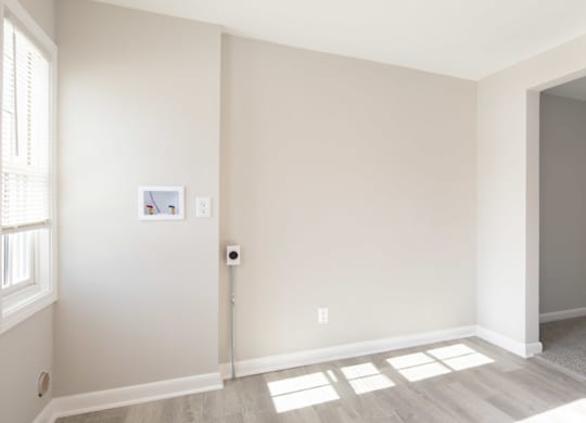 A room with a white door and a window on the left side.