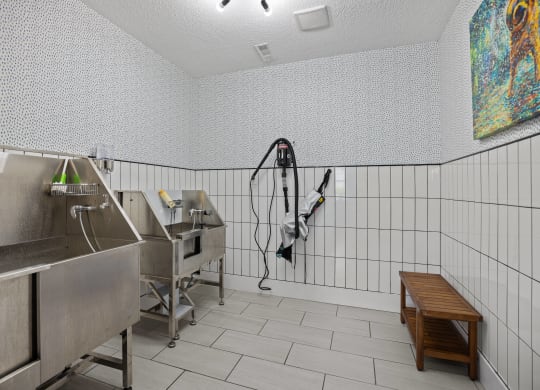 the laundry room has two stainless steel sinks and white tiled walls