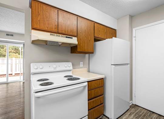 A white stove and refrigerator in a kitchen with wooden cabinets.