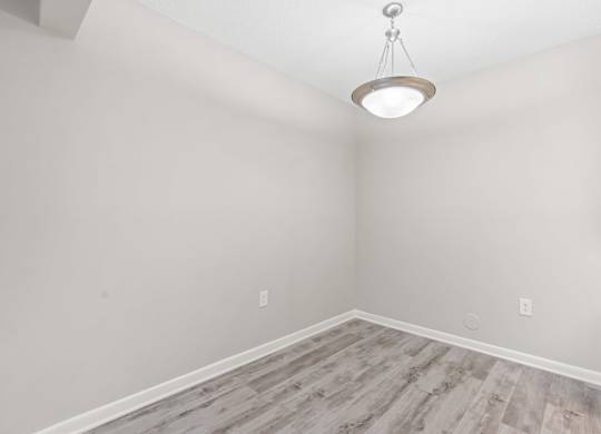 A room with a light hanging from the ceiling and a wooden floor.