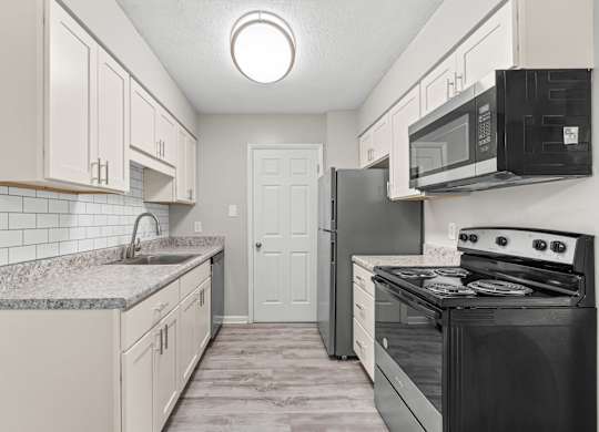 A kitchen with black appliances and white cabinets.