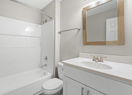 A white bathroom with a toilet, sink, and bathtub.