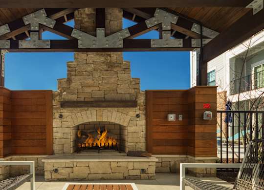 A fireplace is under a wooden beam with a blue sky in the background.