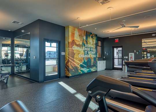 A gym with treadmills and a motivational poster on the wall.