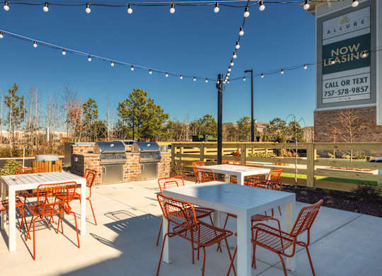 A patio with a table and chairs is set up with a sign that says "Now Leasing" in the background.