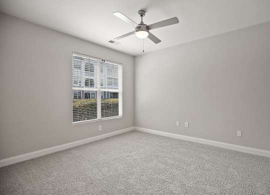 A room with a ceiling fan and a window with blinds.