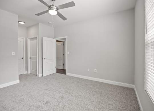 A room with a ceiling fan and carpeted floor.