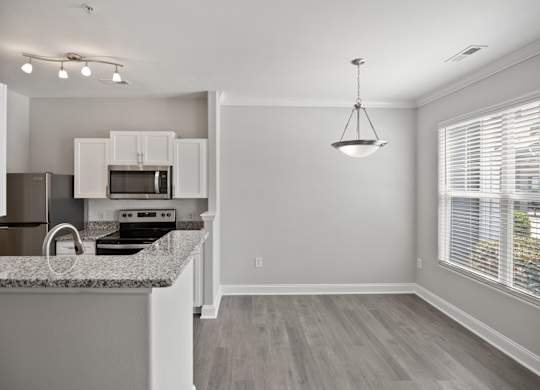 A kitchen with granite countertops and white cabinets.