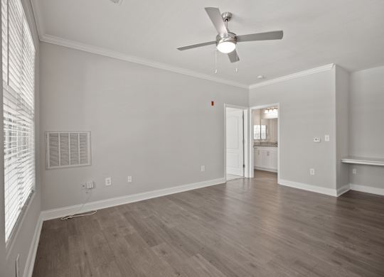 A room with a ceiling fan and wooden flooring.
