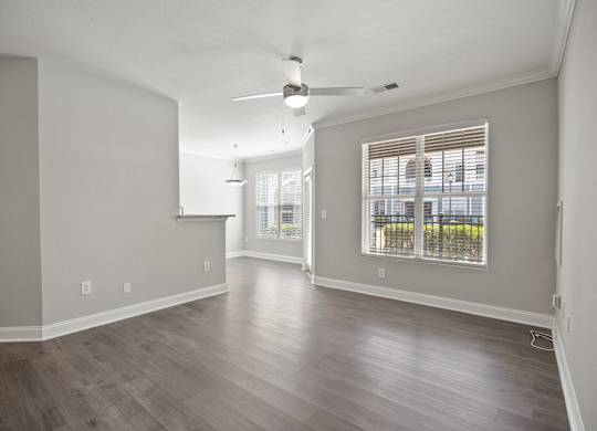 A room with a ceiling fan and a window with blinds.