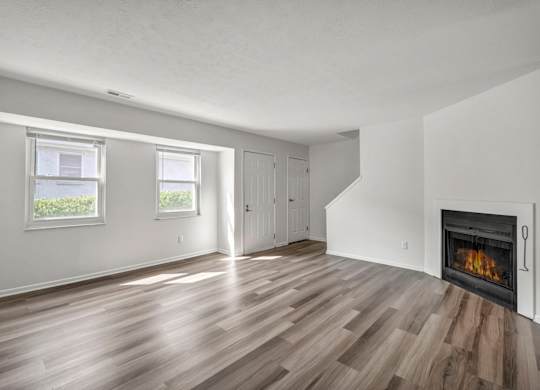 A room with a fireplace and wood flooring.